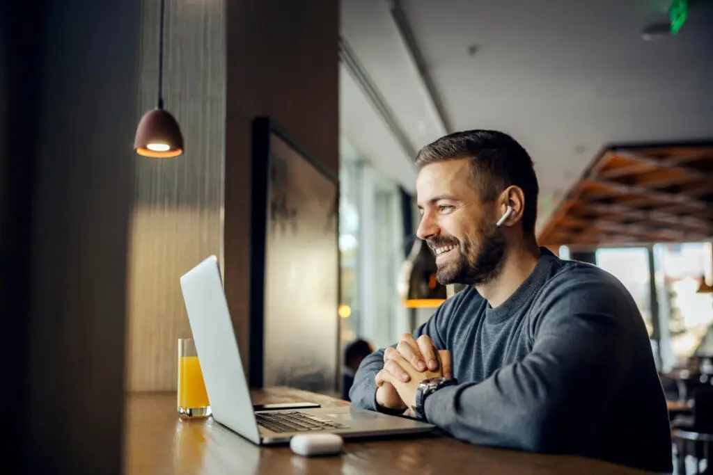 A friendly freelancer is sitting in a coffee shop and having conference call with client