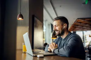 A friendly freelancer is sitting in a coffee shop and having conference call with client