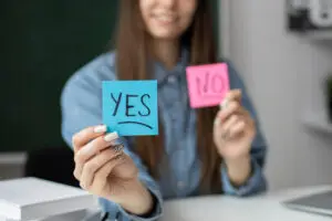 a girl holding two stickers with say yes and no