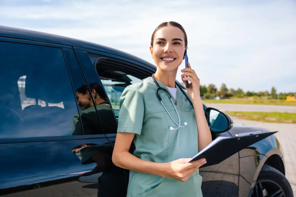 Female doctor standing near the car and talking on the phone
